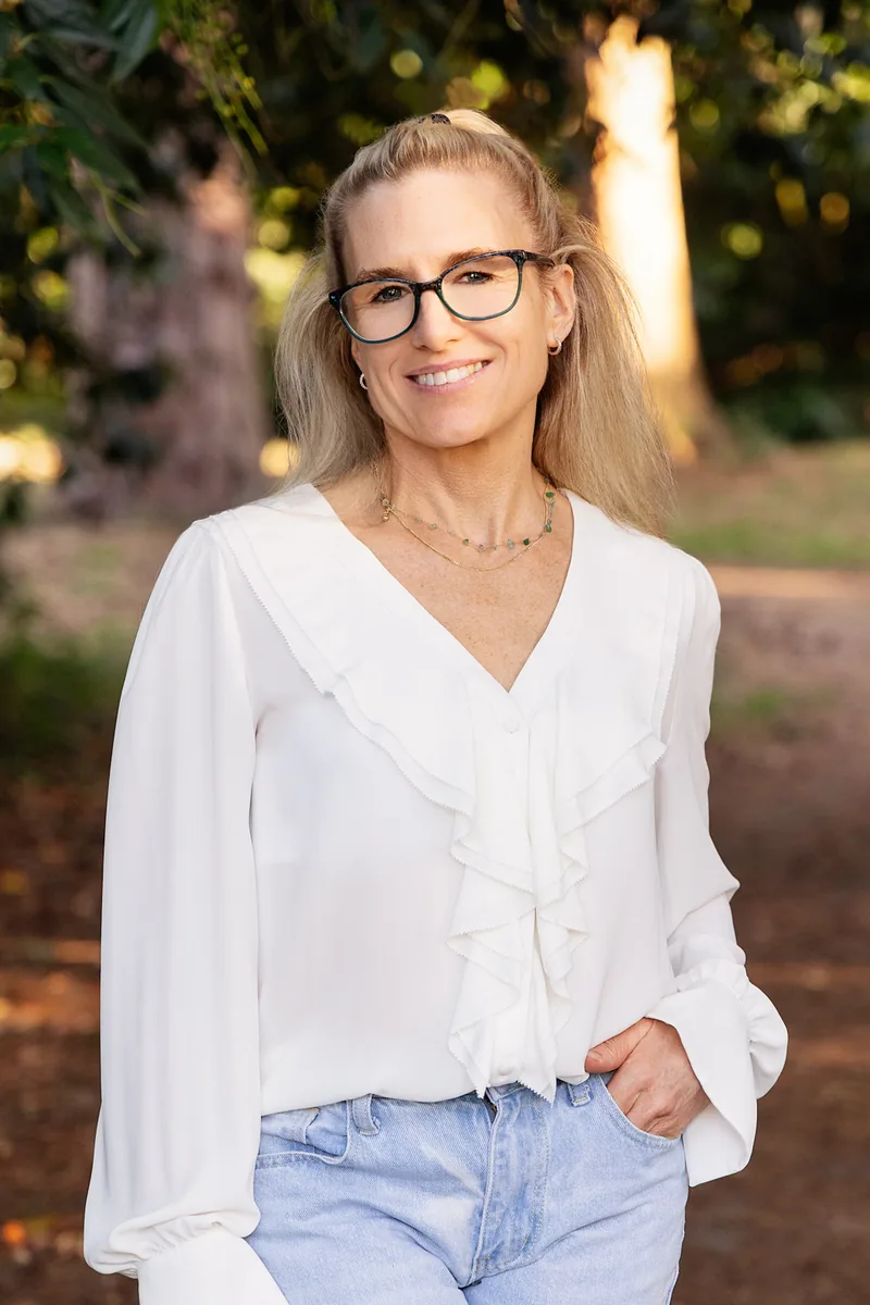 Charlotte Sinclair standing on a tree-lined path in Surrey, smiling towards the camera.